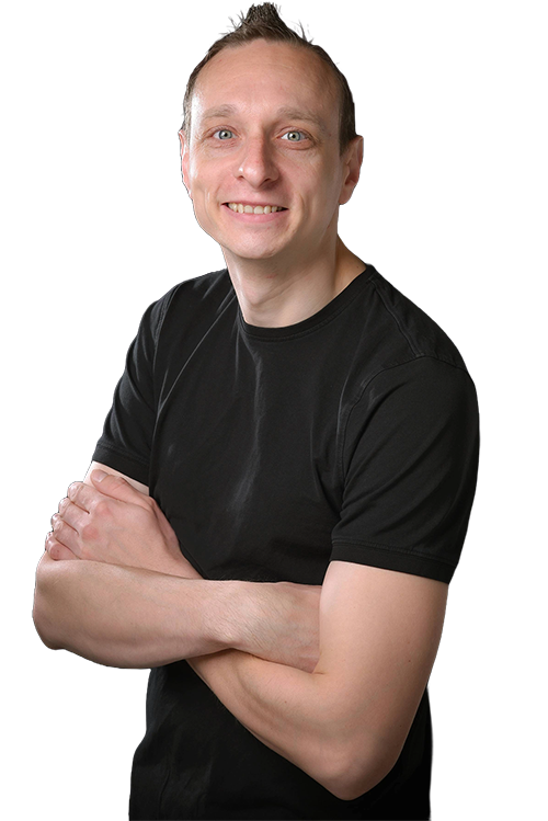 Mann lächelt, trägt schwarzes T-Shirt, Arme verschränkt, kurzer Haarschnitt.